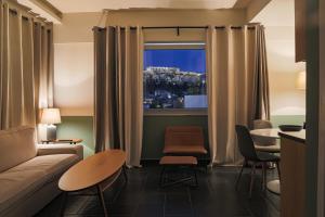 アテネにあるElite Ermou Suitesのリビングルーム(ソファ、テーブル付)、窓が備わります。