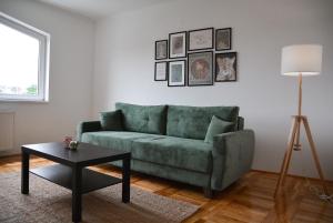 a living room with a green couch and a table at CROWN apartment 2 in Subotica