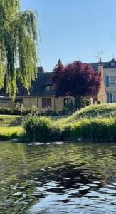 una casa en una colina junto a un cuerpo de agua en La maison du Passeur, en Fillé