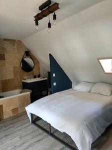 1 dormitorio con cama blanca y bañera en La maison du Passeur, en Fillé