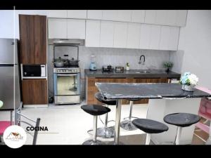 - une cuisine avec un comptoir et quelques tabourets dans l'établissement Hospedaje La Melit, à Tacna