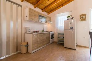 a kitchen with a white refrigerator and wooden cabinets at Little Artemis Cozy Cottage in Argos