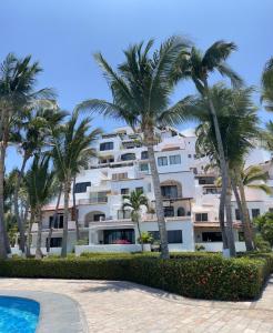 a large white building with palm trees and a swimming pool at CÓMODO DEPARTAMENTO 360 Puerto Las Hadas in Manzanillo