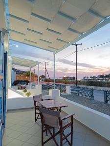 un patio con mesa y sillas y vistas al agua en ΑΥΡΑ Ενοικιαζόμενα Δωμάτια - AVRA Rooms To Let, en Galissas