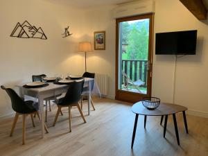 ein Esszimmer mit Tisch und Stühlen und einem Fernseher in der Unterkunft Le Flocon d'Aurouze 522, Appartement 4 personnes, La Joue du Loup in La Joue du Loup