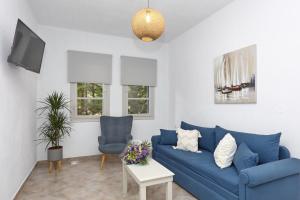 a living room with a blue couch and two chairs at Skopelos Panos Studios in Stafylos