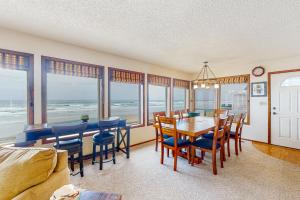 a dining room with a table and chairs and windows at Friend-Ship in Rockaway Beach