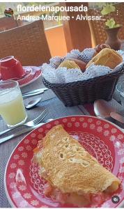 une assiette avec un sandwich sur une table et un panier de pain dans l'établissement Pousada Flor de Lena Icaraizinho - Suíte Jasmim, à Icaraí