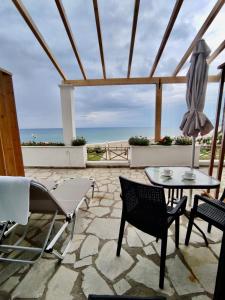un patio con tavolo, sedie e vista sull'oceano di Nereides Apartments ad Agios Gordios