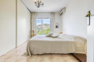 ein weißes Schlafzimmer mit einem Bett und einem Fenster in der Unterkunft Gauguin 44 Almadrava Roses - Immo Barneda in Roses
