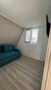 - un salon avec un canapé bleu et une fenêtre dans l'établissement Casa de lemn 2,Tip A, à Corbu