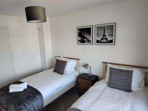 a bedroom with two beds and a lamp on a table at Jarvis Drive 3 Bed contractor house In melton Mowbray in Melton Mowbray