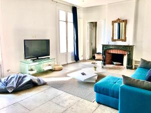 a living room with a blue couch and a tv at Appartement 105 m2 rue Foch Arc de Triomphe hyper centre Montpellier in Montpellier
