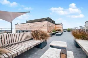 eine Terrasse mit Bänken und Pflanzen auf einem Gebäude in der Unterkunft New Flat (12 mins Central London/Gatwick Airport) in Croydon