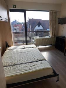 a bedroom with a bed and a large window at THOGE Koksijde in Koksijde