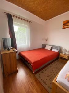 ein Schlafzimmer mit einem roten Bett und einem Fenster in der Unterkunft Fehér Szőlő Vendégház in Sátoraljaújhely