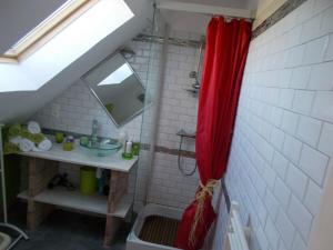 a bathroom with a shower with a red shower curtain at gite Conan in Plourivo