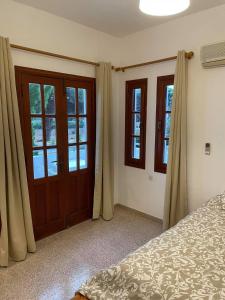 a bedroom with a bed and two doors and windows at Pefkos Filoxenia in Pefki