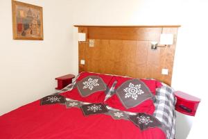 Una cama con sábanas rojas y almohadas de copo de nieve. en Plagne Soleil - Montsoleil -Ski aux pieds-5 personnes, en Plagne Villages