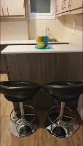 a kitchen with two black stools in front of a counter at Loutraki by the sea in Loutraki