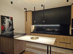 eine Küche mit schwarzen Schränken und einem Holztisch in der Unterkunft ADAV Luxus Apartment in Visoko