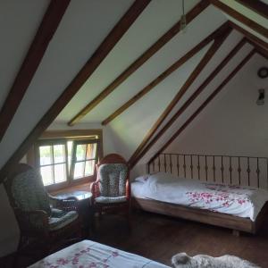 a attic bedroom with a bed and two chairs at Vikendica na Janju in Šipovo
