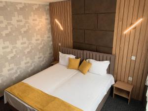 a bedroom with a bed with white sheets and yellow pillows at Hotel Trayana in Stara Zagora