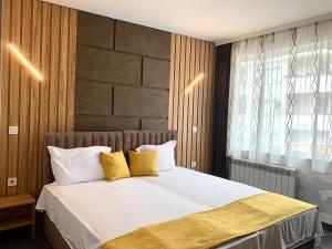 a bedroom with a bed with white sheets and yellow pillows at Hotel Trayana in Stara Zagora