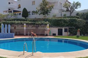 una donna seduta su una sedia accanto alla piscina di El Refugio Paz y Tranquilidad Benalmadena Costa del Sol a Benalmádena