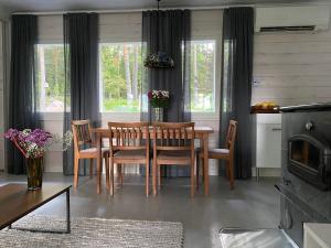 uma sala de jantar com mesa, cadeiras e janelas em Kodikas vapaa-ajan asunto Päijänteen rannalla em Sysmä