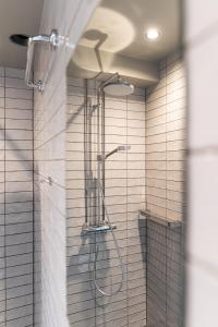 a shower in a bathroom with white tiles at Billnäsin ruukki in Billnäs