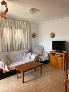 a living room with a couch and a flat screen tv at Alcossebre, Apartamentos Hibiscus in Alcossebre