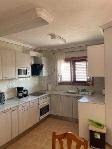 a kitchen with white cabinets and a stove top oven at Alcossebre, Apartamentos Hibiscus in Alcossebre