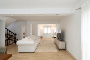 Sala de estar blanca con sofá blanco y TV en Casa Malvina en Calonge