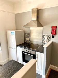 una pequeña cocina con fogones y nevera. en 2 bed flat, 1 bed flat Torquay, Torbay, Devon, en Torquay