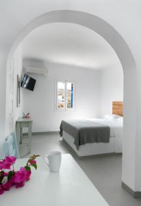 a white bedroom with a bed and a table with flowers at Firoa Studios in Donoussa