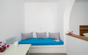 Habitación con cama con sábanas azules y mesa. en Firoa Studios en Donoussa