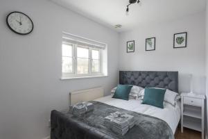 a bedroom with a bed with a clock on the wall at Detached House - 5 mins drive to City Centre - Free Parking, Fast Wi-Fi and Smart TV with Sky TV and Netflix by Yoko Property in Milton Keynes