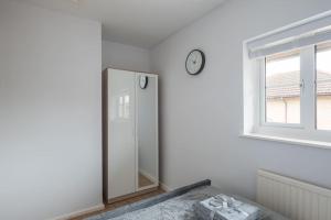 uma casa de banho com um espelho e um relógio na parede em Detached House - 5 mins drive to City Centre - Free Parking, Fast Wi-Fi and Smart TV with Sky TV and Netflix by Yoko Property em Milton Keynes