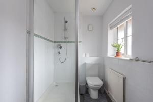 uma casa de banho branca com um chuveiro e um WC. em Detached House - 5 mins drive to City Centre - Free Parking, Fast Wi-Fi and Smart TV with Sky TV and Netflix by Yoko Property em Milton Keynes