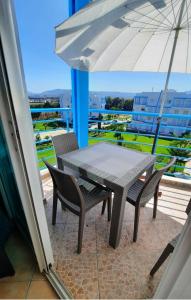 einen Tisch und Stühle auf einem Balkon mit Sonnenschirm in der Unterkunft Lovely Apartment in CABO, RIVIERA BEACH in Cabo Negro