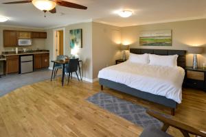 a bedroom with a large bed and a kitchen at Above the Beach Guest Suites in Penticton