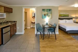 eine Küche und ein Schlafzimmer mit einem Bett und einem Tisch in der Unterkunft Above the Beach Guest Suites in Penticton