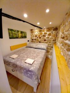 a bedroom with a large bed in a stone wall at RABSKI DVOR in Rab