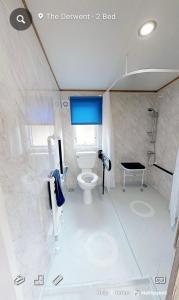 een witte badkamer met een toilet en een douche bij Emma's Pad at Hoburne Naish - New Forest - Wheel chair Accessible with wetroom and ramp in Highcliffe