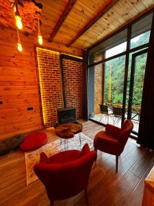 sala de estar con sillas rojas y chimenea en Deredekal suit bungalov, en Çamlıhemşin