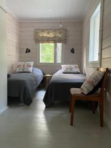 1 dormitorio con 2 camas, silla y ventana en Kodikas vapaa-ajan asunto Päijänteen rannalla, en Sysmä