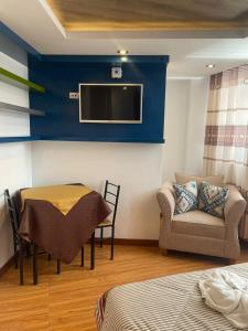 um quarto com uma mesa, um sofá e uma televisão em HOTEL KILLASUMAQ em Cajamarca