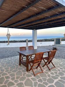 a wooden table and two chairs under a pavilion at the beach at Onar Luxury Villa - Adults Only in Lachania