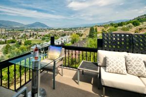 a balcony with a glass table and chairs and a view at Above the Beach Guest Suites in Penticton